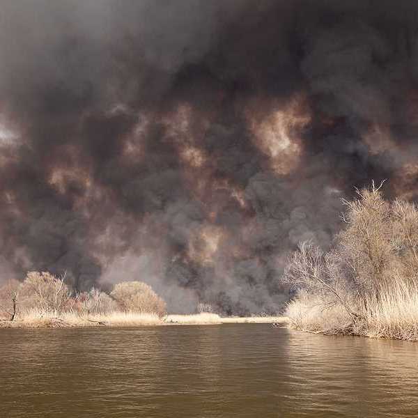 A view of a lake with billowing wildfire smoke in the background