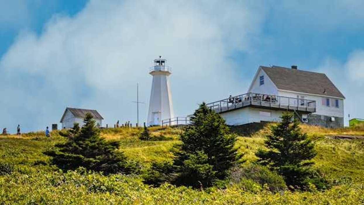 A view of a lighthouse from below a grassy hill