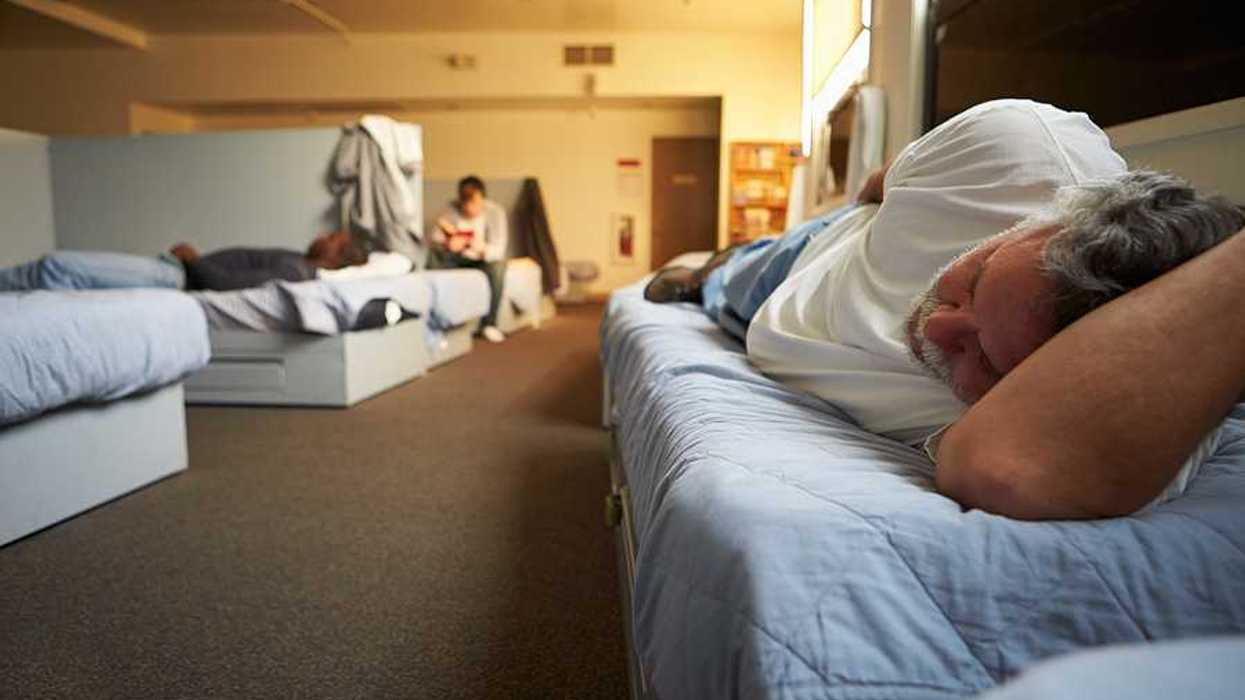 A view of a man lying on a bed in a homeless shelter