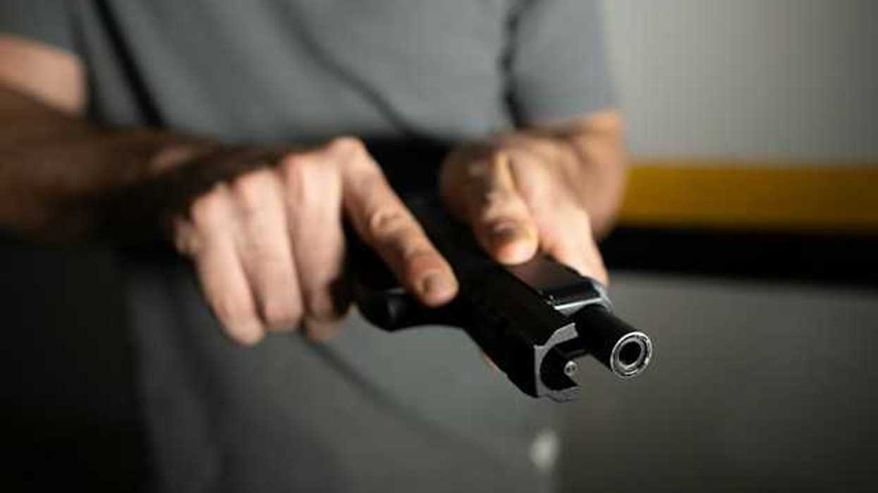 A view of a man's hand holding a black gun