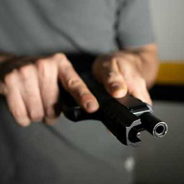 A view of a man's hand holding a black gun