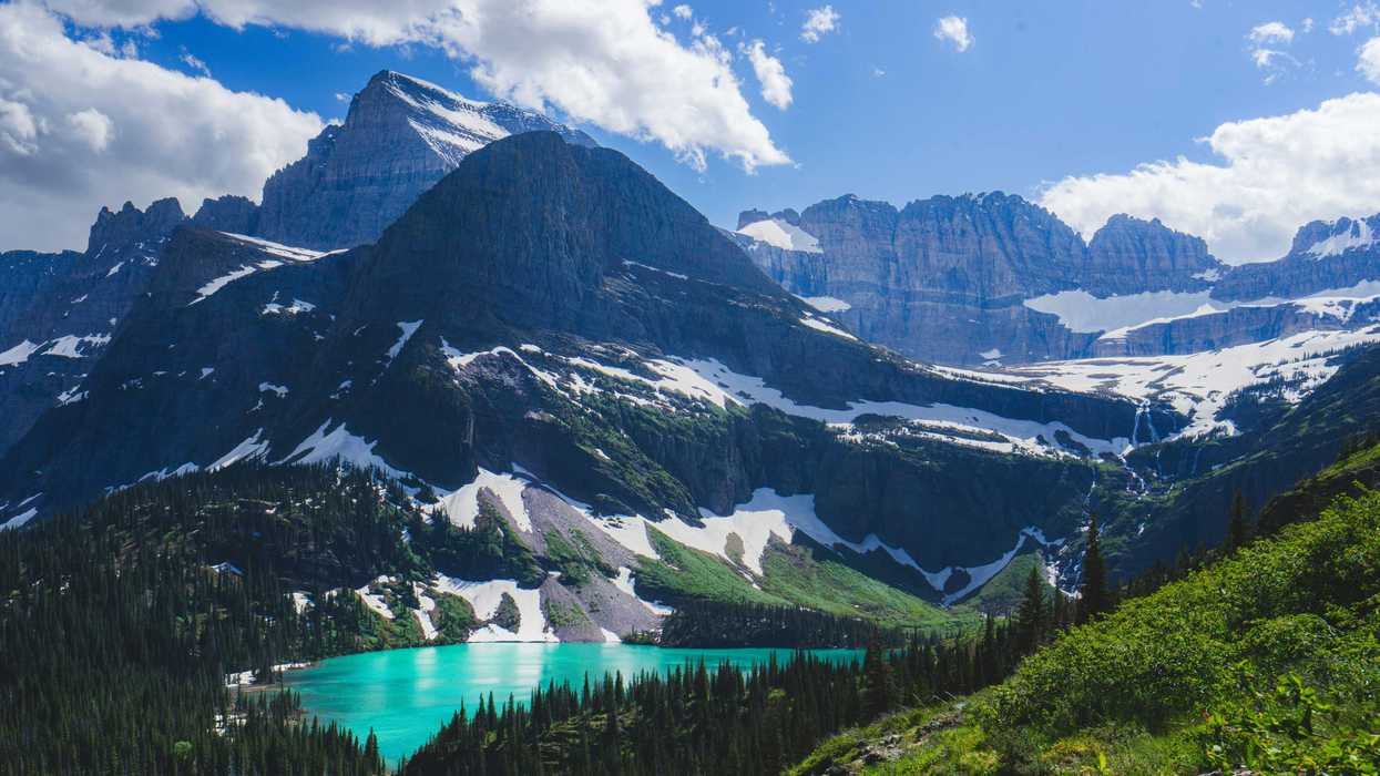 a view of a mountain range with glaciers, and a lake in the foreground.