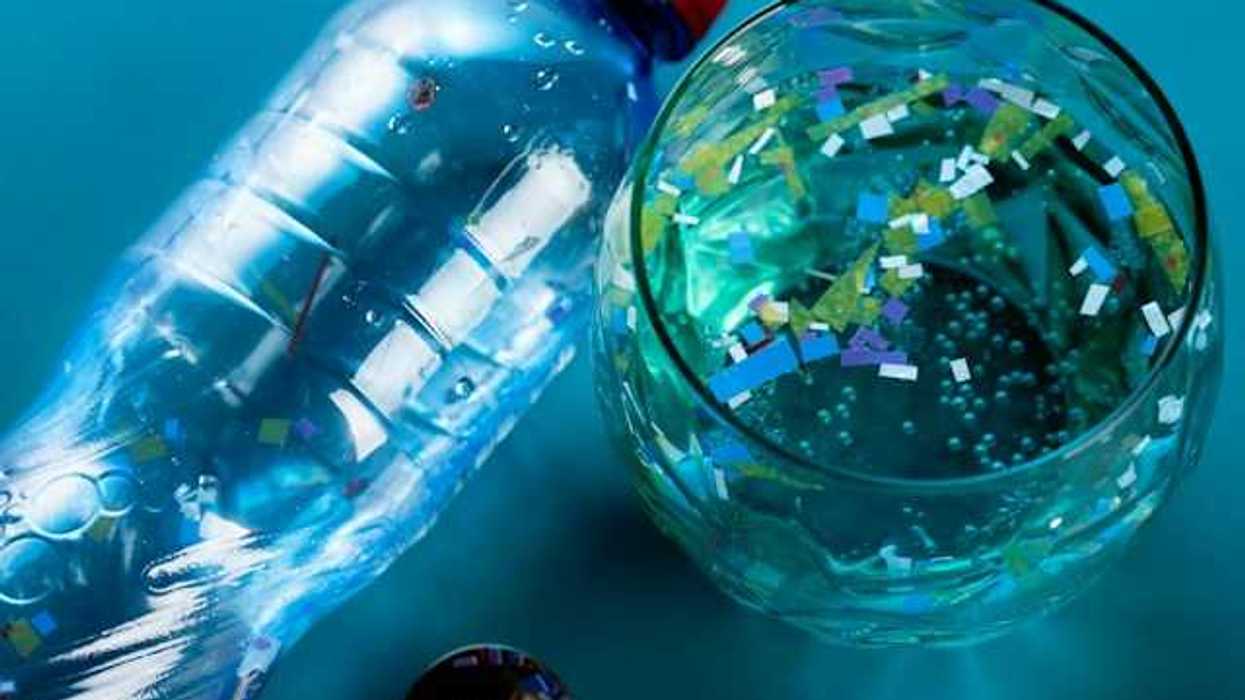 A view of a plastic bottle of water and a glass with water and small bits of plastic in it
