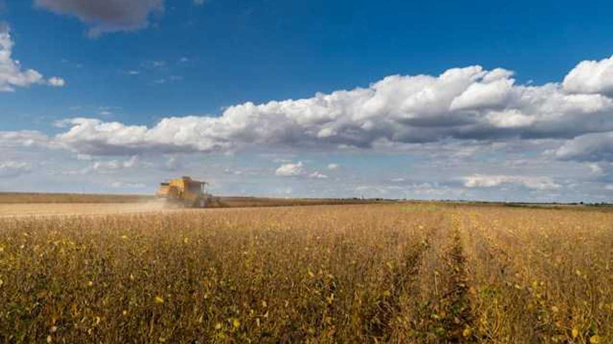 A view of a prairie farm field with a tractor in the distance