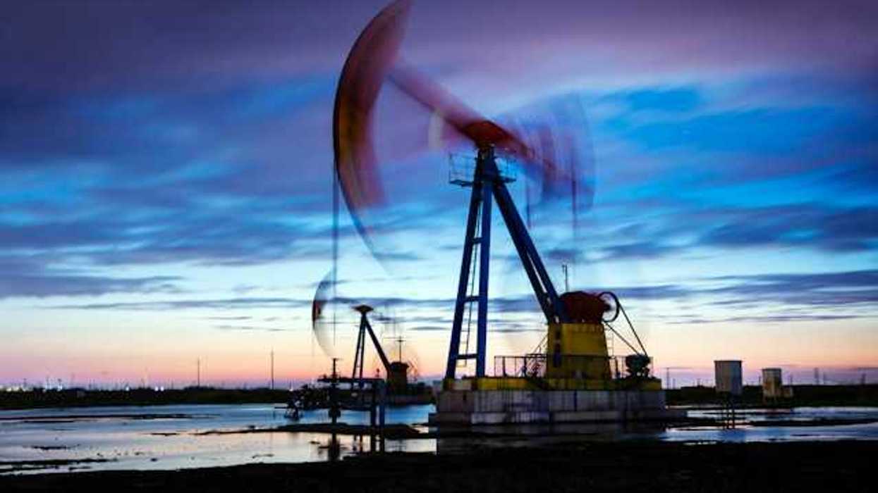 A view of a pump jack drilling for oil with the sunset in the background