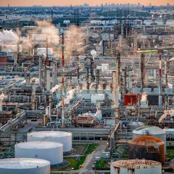 A view of a refinery with a city skyline in the background