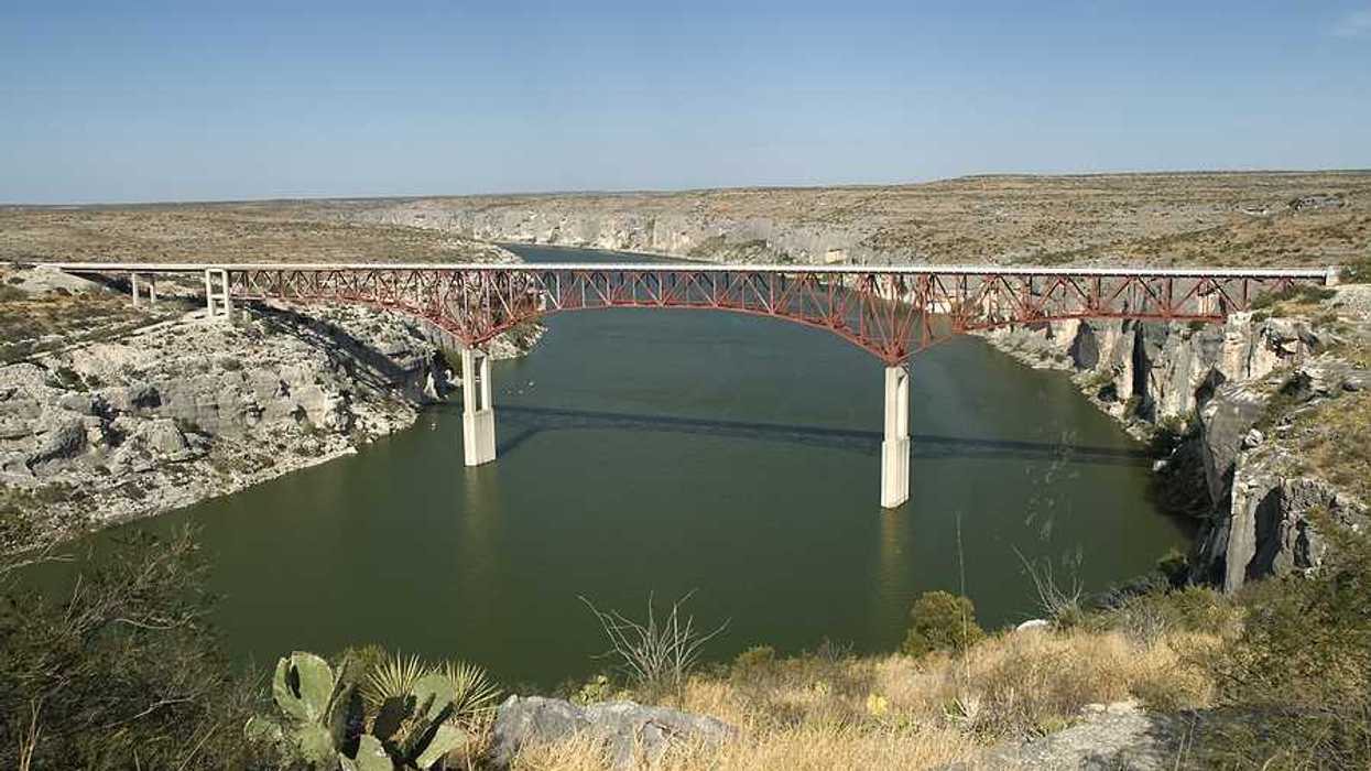 A view of a river flowing under a bridge in a dry landscape