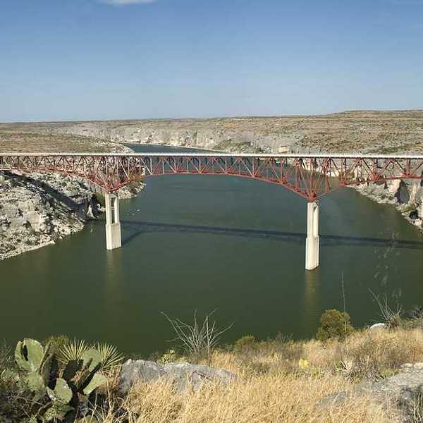 A view of a river flowing under a bridge in a dry landscape