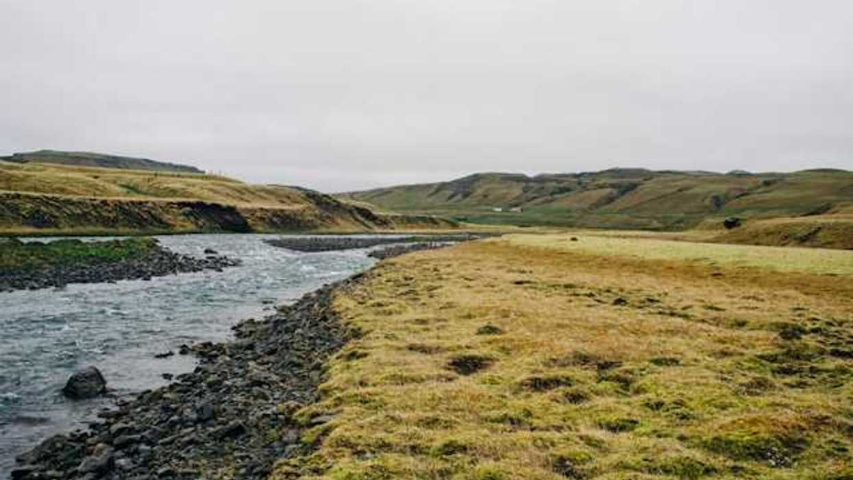A view of a river with low hills and peatland in the distance