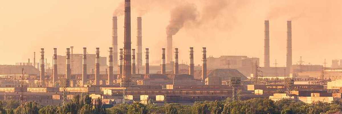 A view of a steel mill with smokestacks emitting billowing clouds of smoke