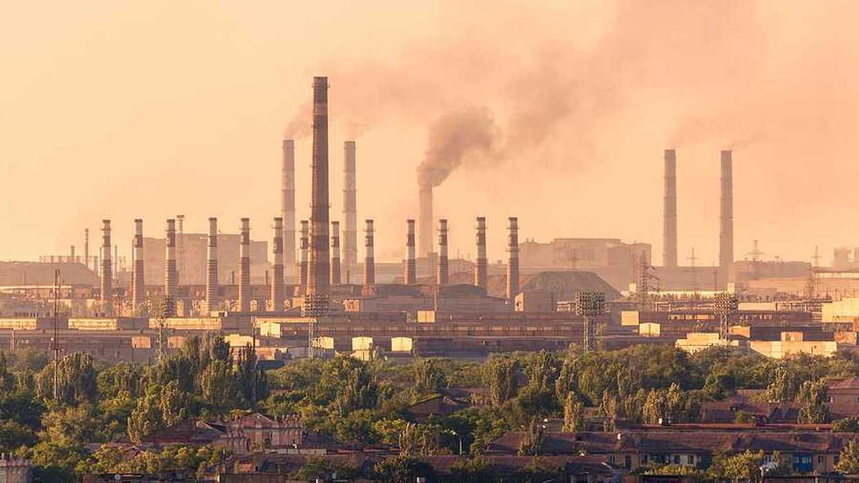 A view of a steel mill with smokestacks emitting billowing clouds of smoke