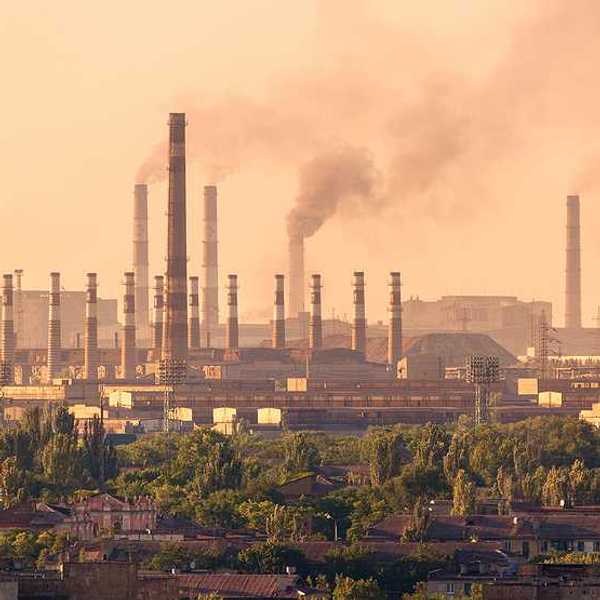 A view of a steel mill with smokestacks emitting billowing clouds of smoke