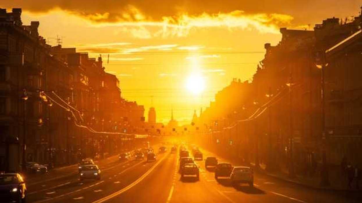 A view of a street in a European city with the setting sun in the background
