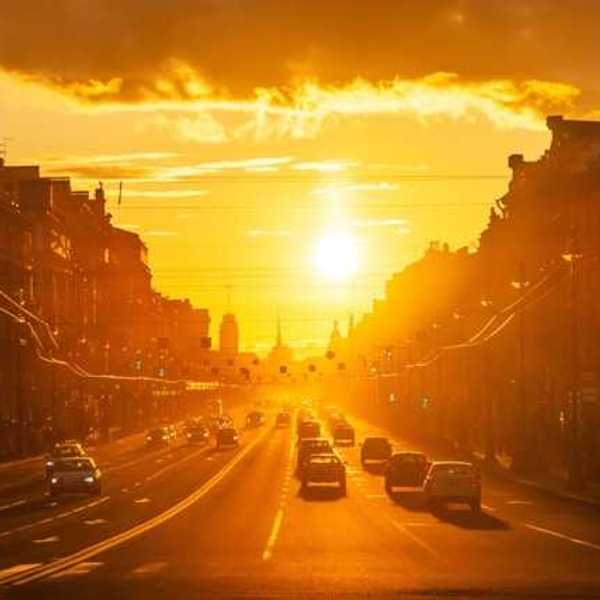 A view of a street in a European city with the setting sun in the background