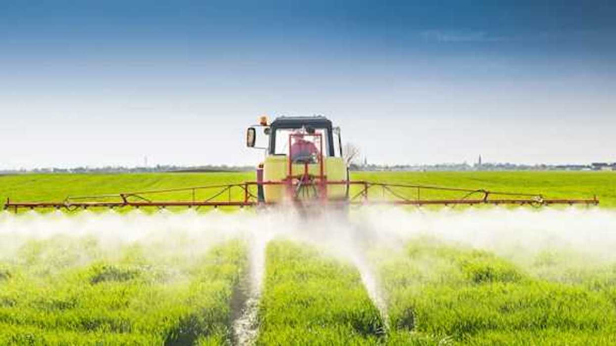 A view of a tractor applying pesticides to a field