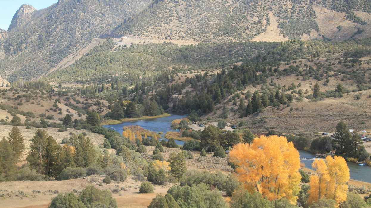 a view of a valley with a river and mountains in the background.