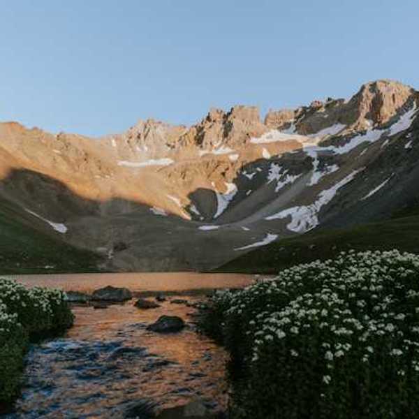 A view of a valley with mountains in the background with melting snow on their banks