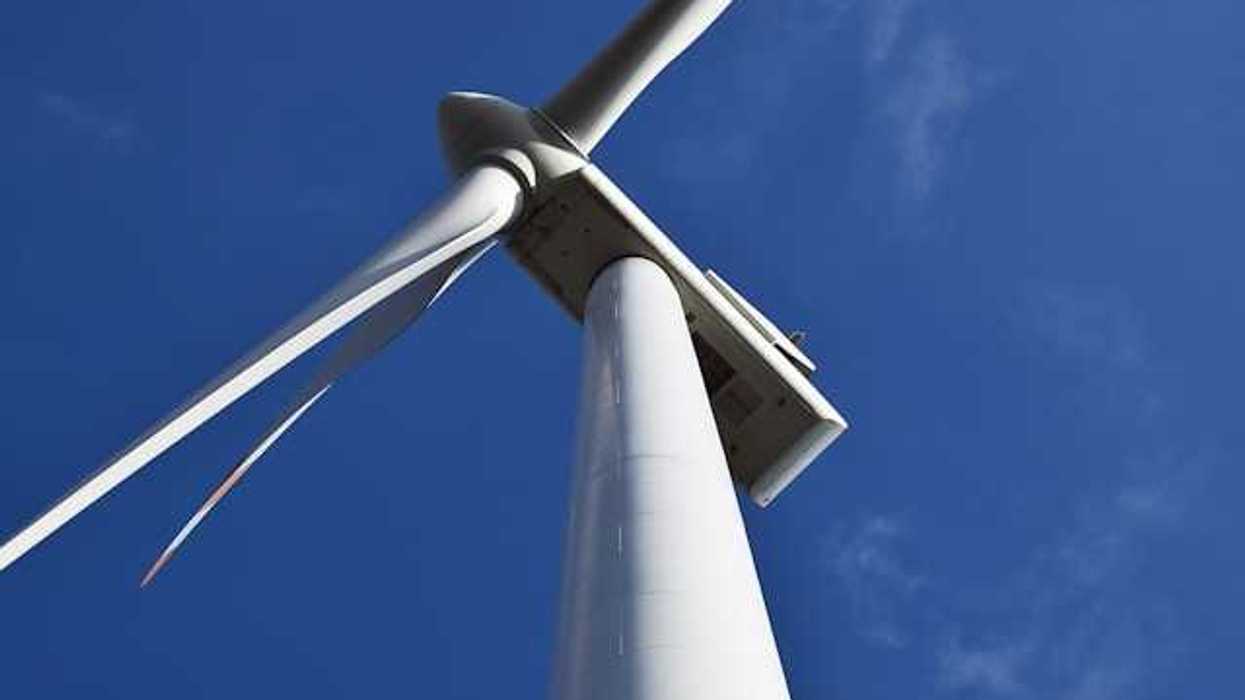 A view of a wind turbine from below against a blue sky