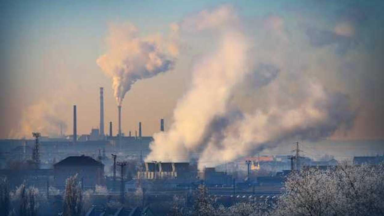 A view of an industrial area with smoke billowing out of smokestacks