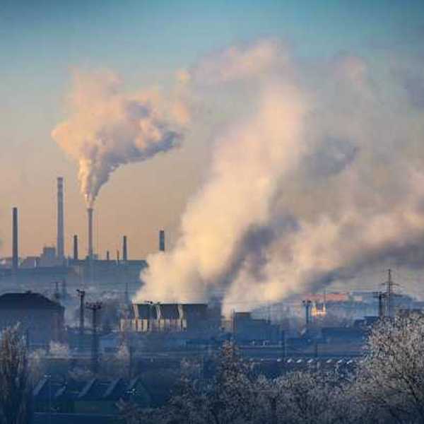 A view of an industrial area with smoke billowing out of smokestacks