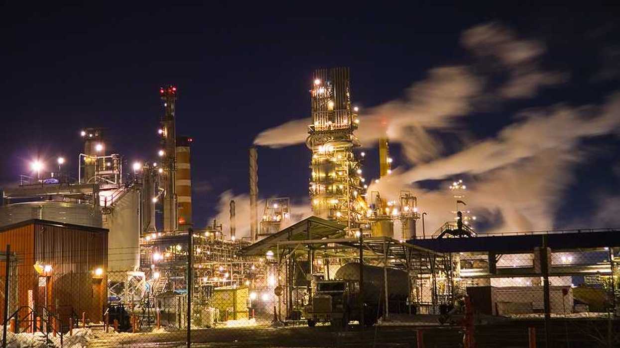 A view of an industrial plant with smoke billowing from smokestacks