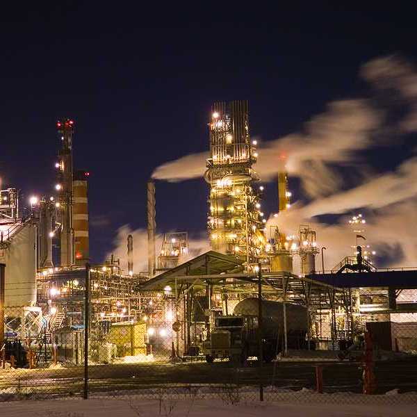 A view of an industrial plant with smoke billowing from smokestacks