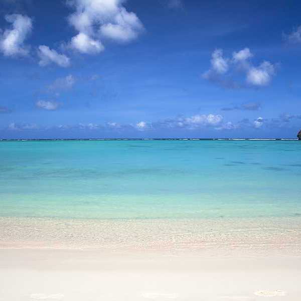 A view of aqua water and a white sand beach under a blue sky