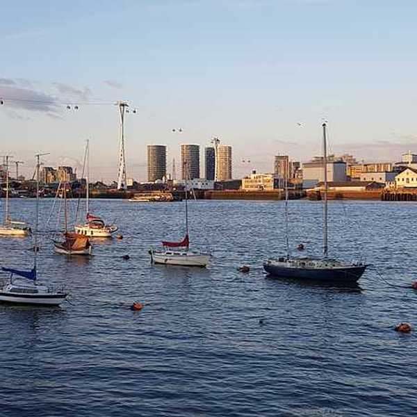 A view of boats floating on the Thames with buildings in the background