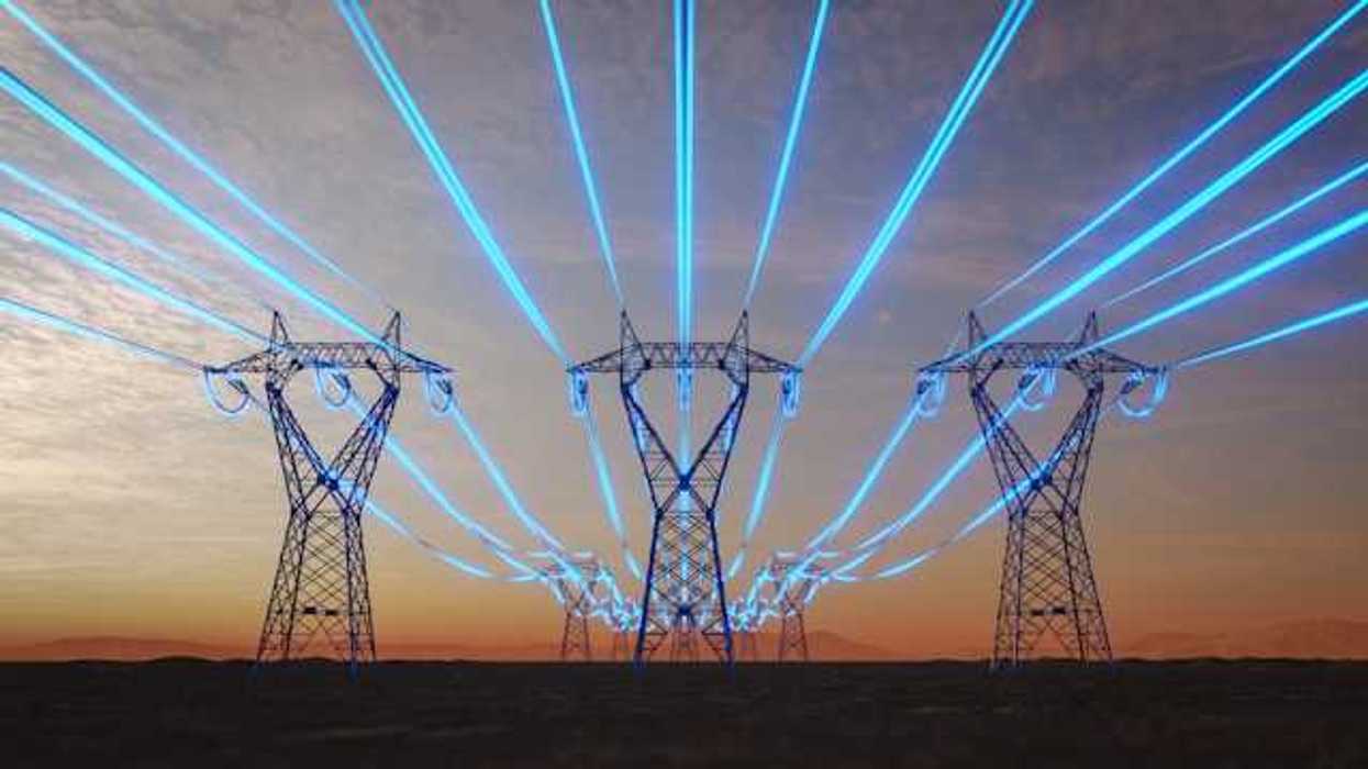A view of electricity towers with blue wires stretching into the distance against a red sky during sunset