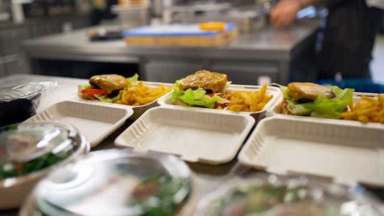 A view of food containers in a kitchen filled with burgers, fries and salad