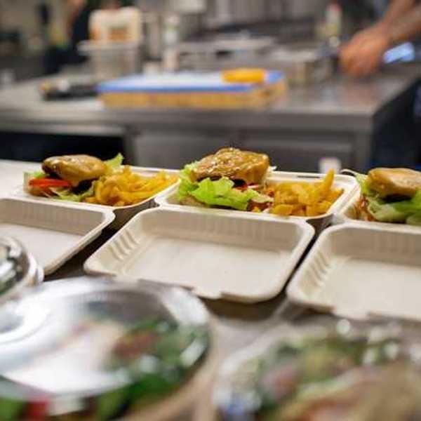 A view of food containers in a kitchen filled with burgers, fries and salad