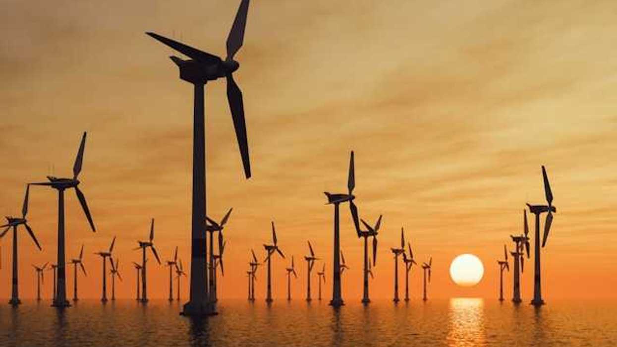 A view of many offshore wind turbines with the setting sun in the distance