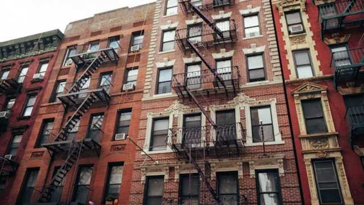 A view of New York City brick apartment buildings with fire escapes on the sides of the building