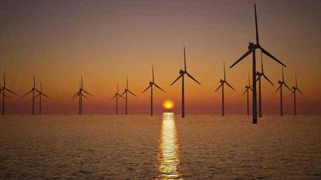 A view of offshore wind turbines with the setting sun in the distance