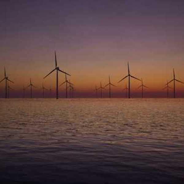 A view of offshore wind turbines with the sunset in the background