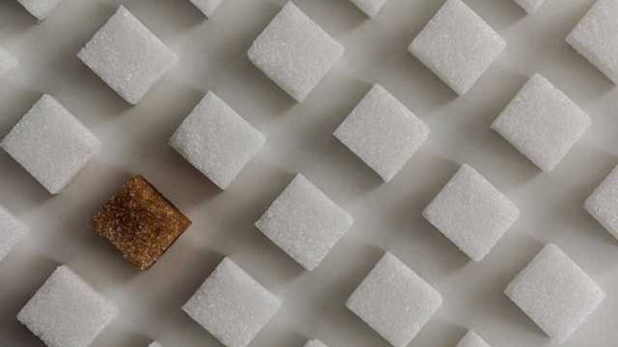 A view of rows of white sugar cubes with one brown sugar cube