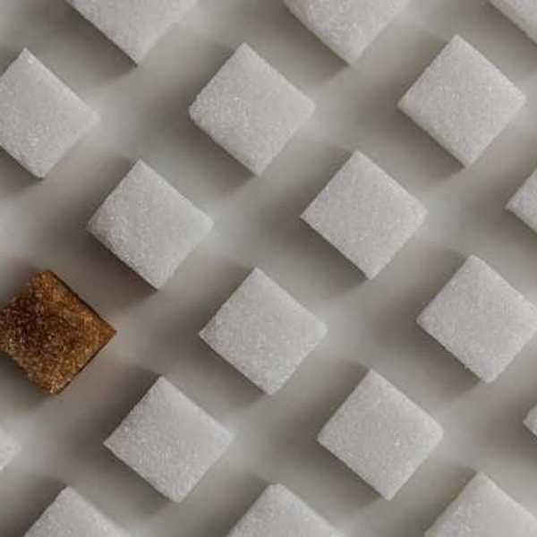 A view of rows of white sugar cubes with one brown sugar cube