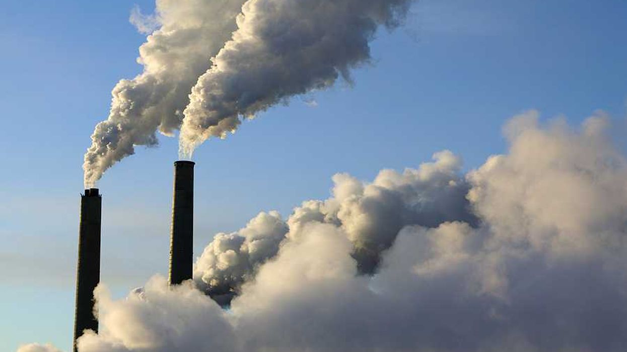 A view of smokestacks spewing smoke into a blue sky