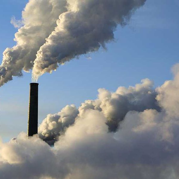 A view of smokestacks spewing smoke into a blue sky