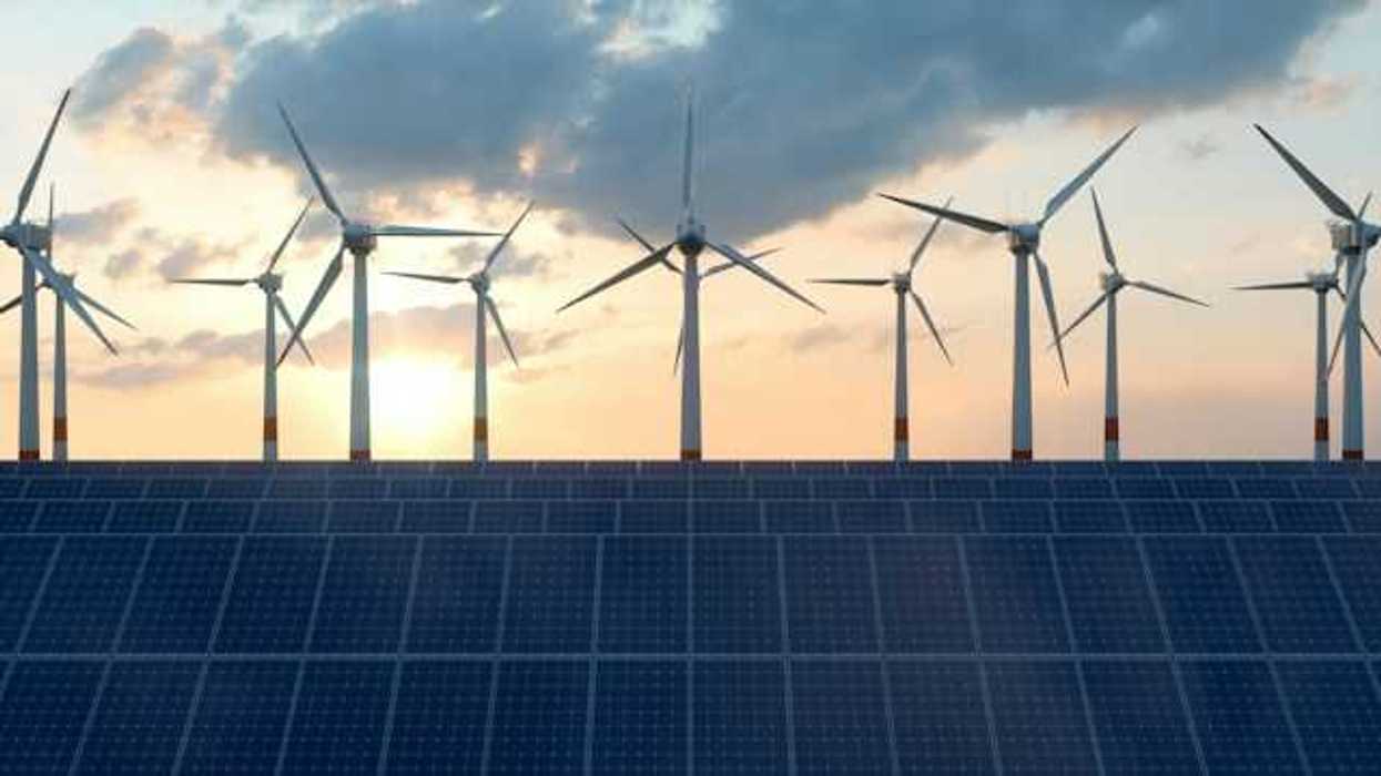 A view of solar panels with wind turbines in the background
