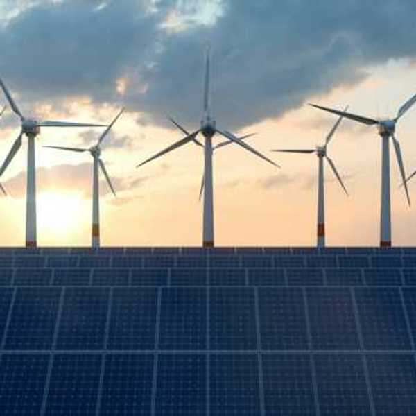 A view of solar panels with wind turbines in the background