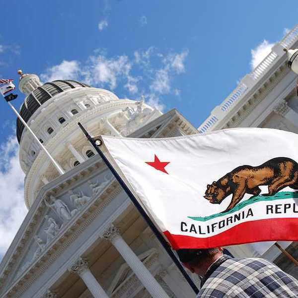A view of the California flag flying next to the California capitol building