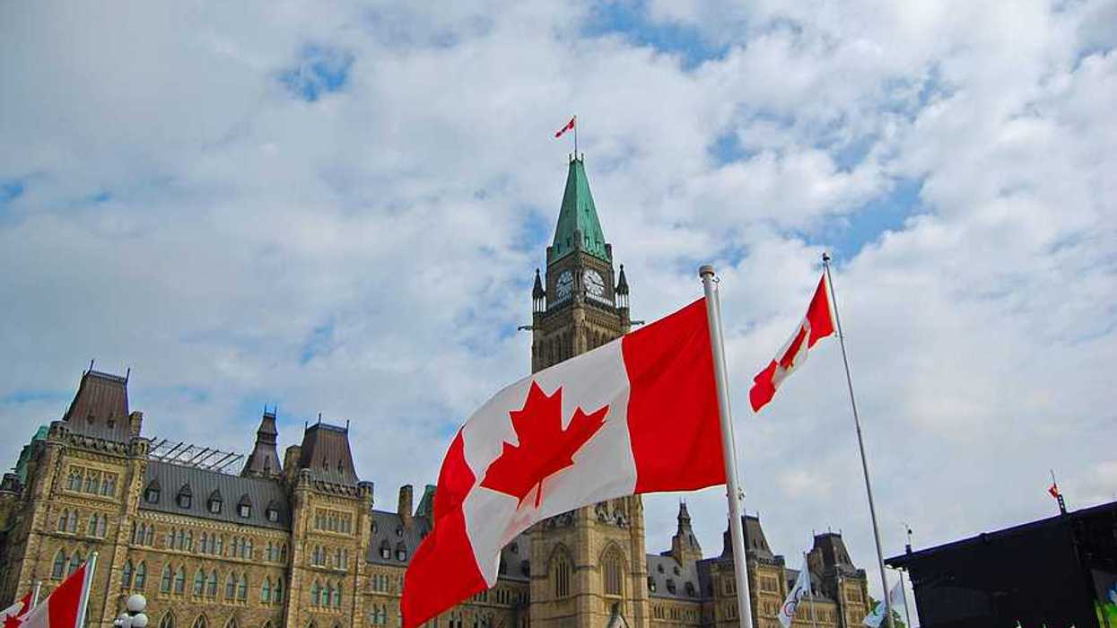 A view of the Canadian parliament building with Canadian flags flying outside