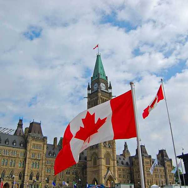 A view of the Canadian parliament building with Canadian flags flying outside
