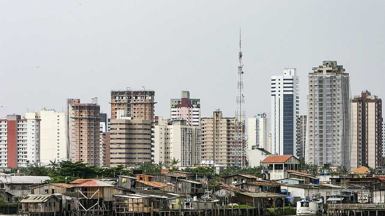 A view of the city of Belem in Brazil with huts by the ocean and skyscrapers in teh background