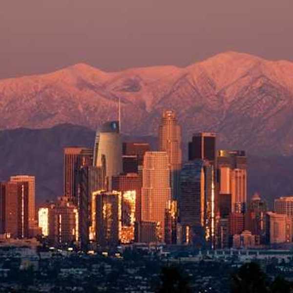 A view of the Denver skyline at dusk with the moon rising behind the mountains