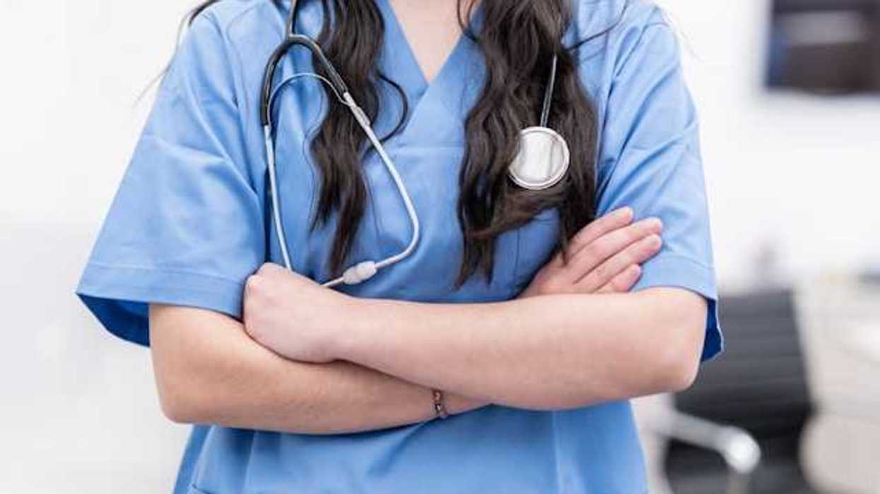 A view of the midsection of a female health worker wearing scrubs and a stethoscope