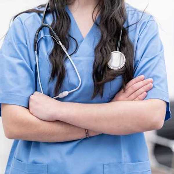 A view of the midsection of a female health worker wearing scrubs and a stethoscope