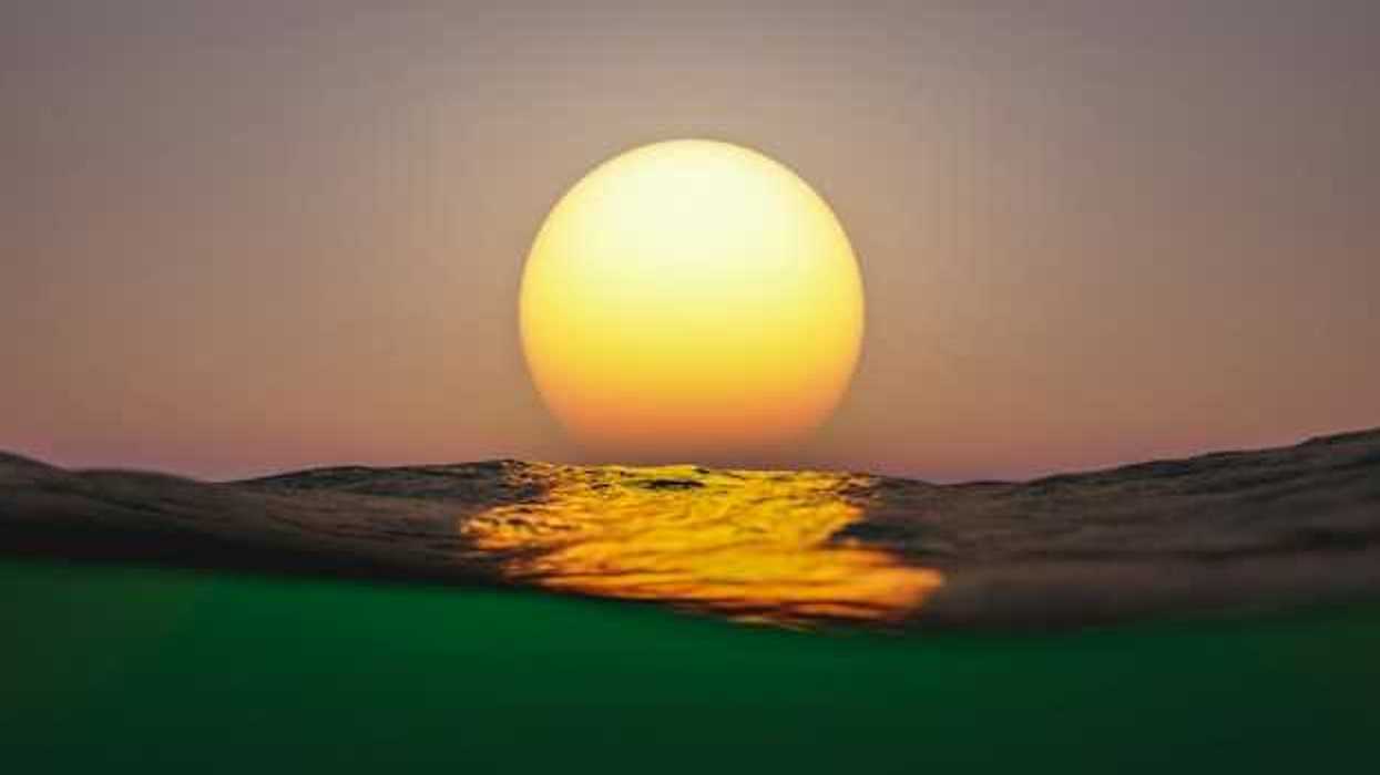 A view of the setting sun with ocean water in the foreground