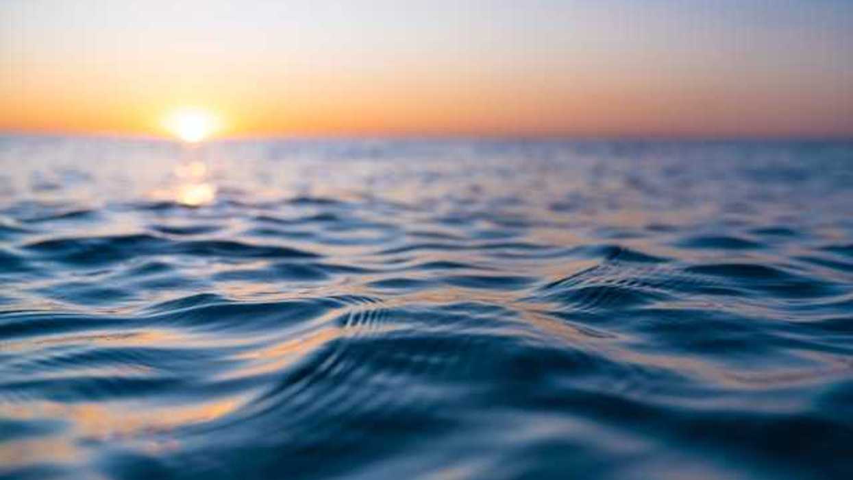A view of the surface of the sea with the setting sun in the distance